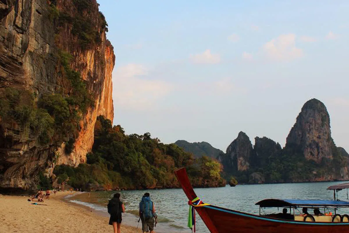 A classic Krabi shoreline with a long-tail boat and sea stacks off Railay.