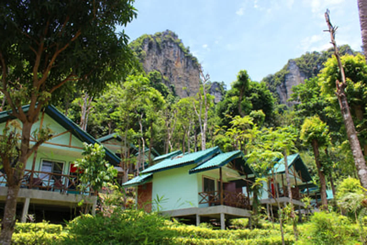 White bungalows with green roofs set below steep limestone cliffs in Tonsai.